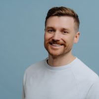 vecteezy_handsome-cheerful-bearded-man-smiles-gladfully-dressed-in_7421470